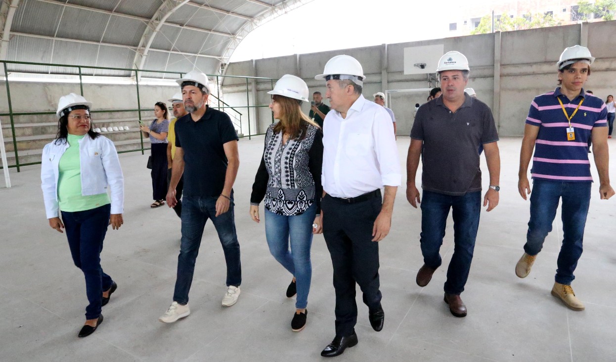 grupo de pessoas caminha em uma quadra de uma escola em obras